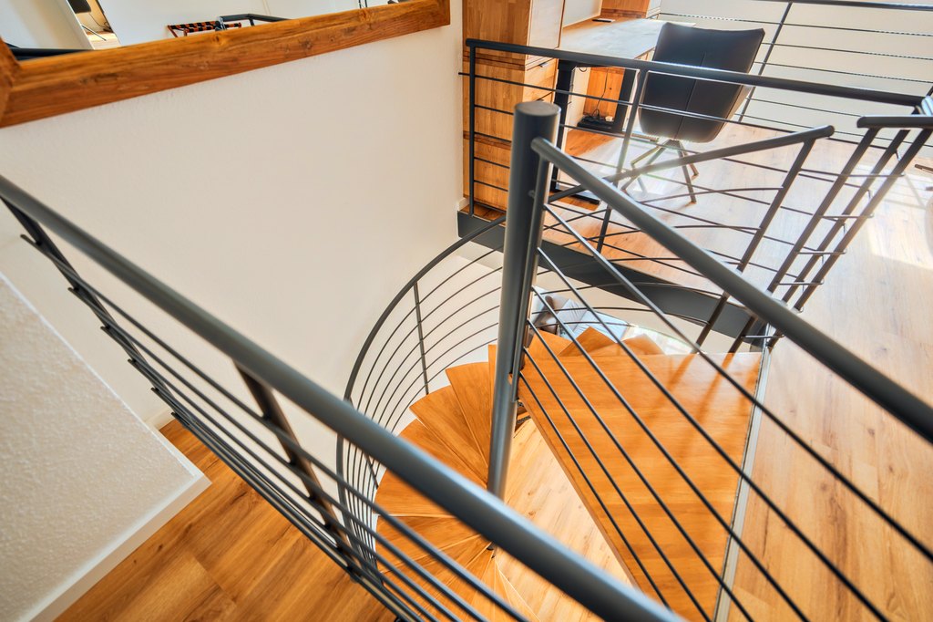 Blick von oben auf eine Wendeltreppe mit Holzstufen
